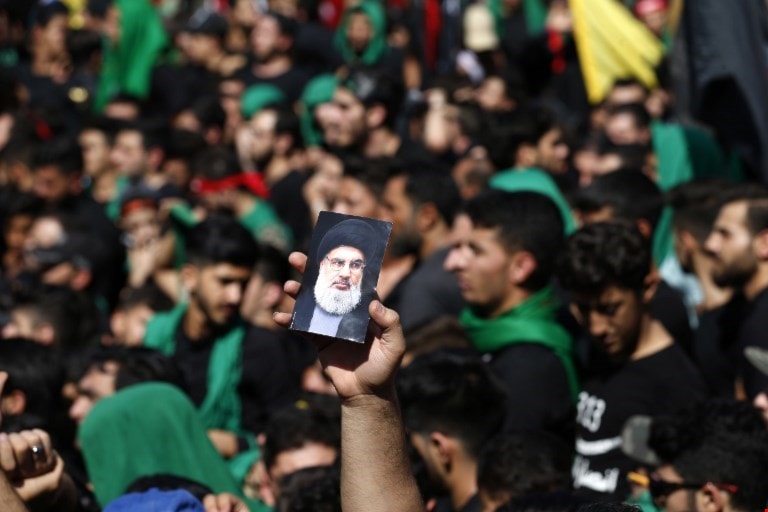 صورة السيد نصر الله خلال مسيرة العاشر من محرم بيد أحد مناصريه (أ ف ب) صورة السيد نصر الله خلال مسيرة العاشر من محرم بيد أحد مناصريه (أ ف ب)