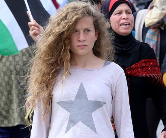 البطلة الفلسطينية عهد التميمي وقفت في قاعة المحكمة العسكرية بغرب رام الله، مقيّدة القدمين بسلاسل داخل قفص حديدي محاطة بأربعة حراس من شرطة الاحتلال الإسرائيلي البطلة الفلسطينية عهد التميمي وقفت في قاعة المحكمة العسكرية بغرب رام الله، مقيّدة القدمين بسلاسل داخل قفص حديدي محاطة بأربعة حراس من شرطة الاحتلال الإسرائيلي
