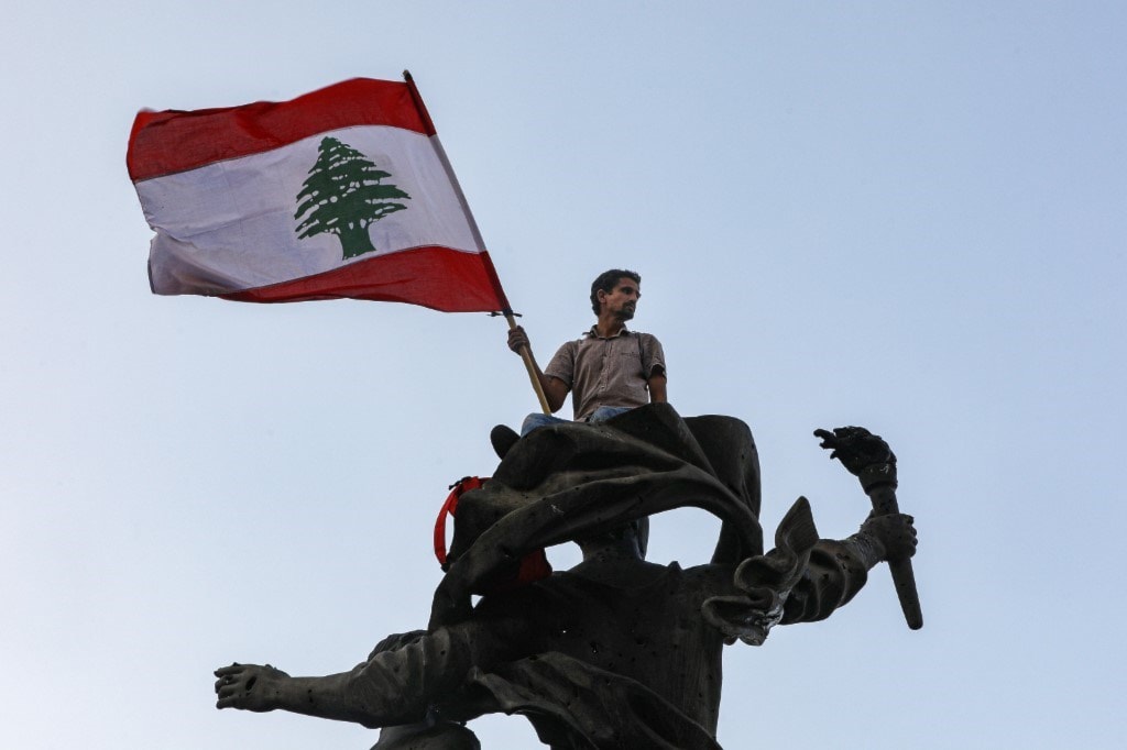 متظاهر يرفع العلم اللبناني على تمثال الشهداء وسط بيروت (أ ف ب) متظاهر يرفع العلم اللبناني على تمثال الشهداء وسط بيروت (أ ف ب)