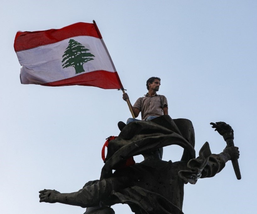 متظاهر يرفع العلم اللبناني على تمثال الشهداء وسط بيروت (أ ف ب) متظاهر يرفع العلم اللبناني على تمثال الشهداء وسط بيروت (أ ف ب)