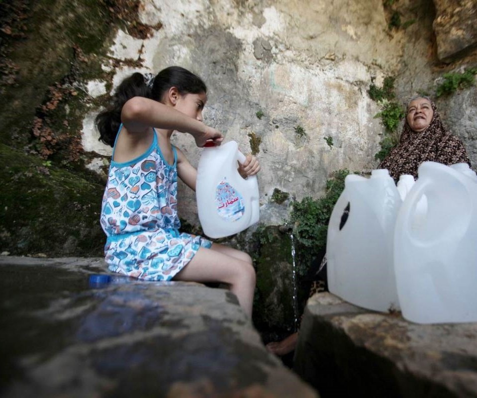 فتاة فلسطينية تملأ عبوات المياه من نبع في الضفة الغربية. فتاة فلسطينية تملأ عبوات المياه من نبع في الضفة الغربية.