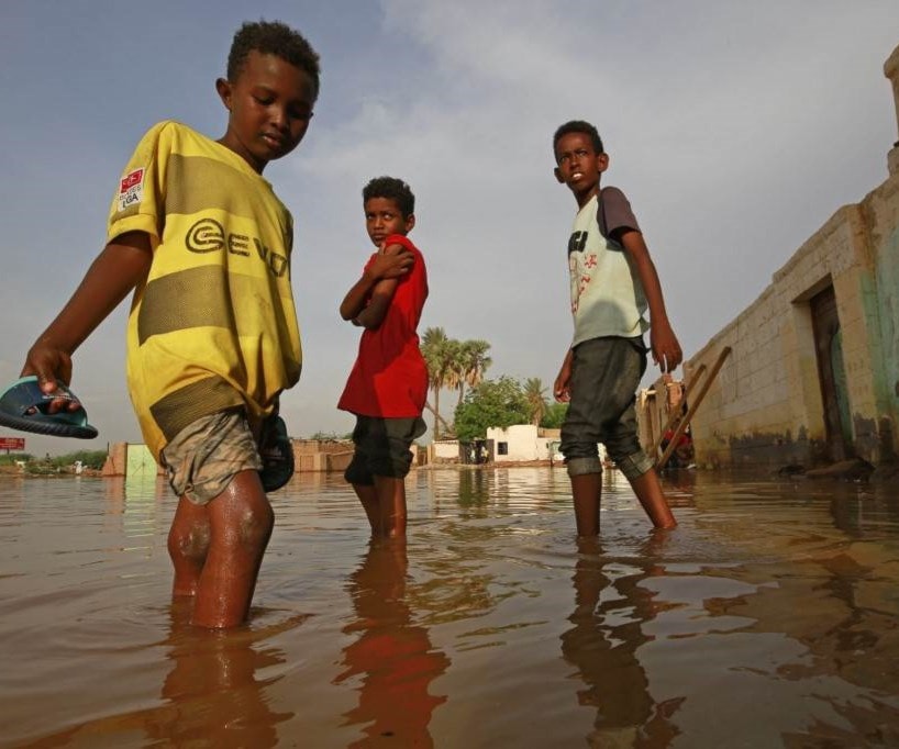 أطفال يشقون طريقهم عبر شارع غمرته المياه في السودان (أ ف ب). أطفال يشقون طريقهم عبر شارع غمرته المياه في السودان (أ ف ب).