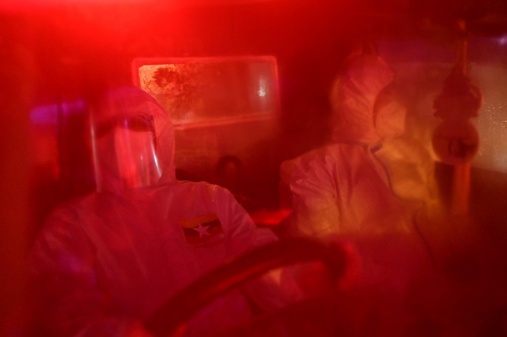 متطوعون داخل سيارة إسعاف حيث يتم نقل المشتبه بإصابتهم بكورونا في يانغون (أ ف ب).