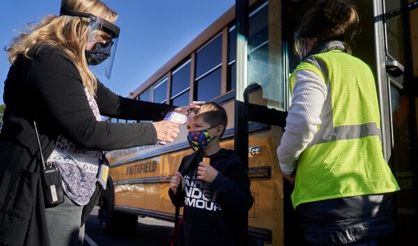 معلمة تفحص درجة حرارة تلميذ في مدرسة ابتدائية في الولايات المتحدة.