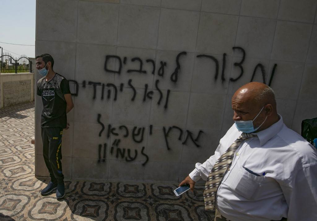 فلسطينيون يتفقدون الأضرار التي لحقت بمسجد البيرة الذي تمّ رشه بالكتابات العبرية (أ ف ب).