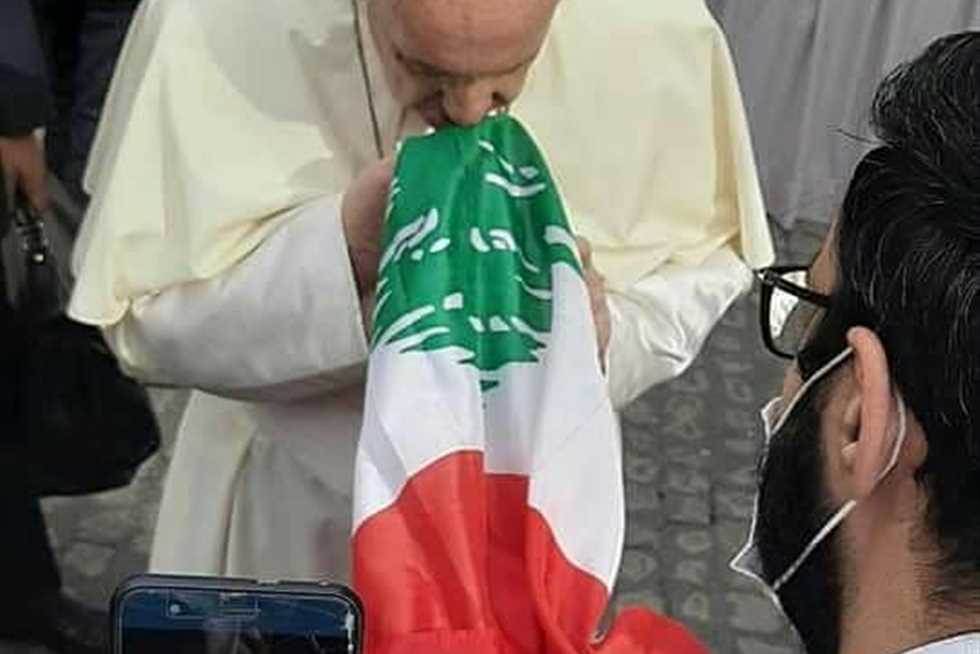 كاهن لبناني يقدم العلم اللبناني للبابا الذي أمسك به وقبله