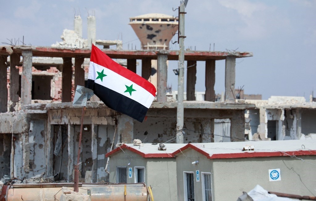 The Syrian flag over the damaged buildings in the Daraa al-Balad region (AFP).